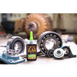 A photo of a bottle of GorilliaPro AR200 green press fit retaining compund in an industrial shop next to various bearings and flanges. (Product image)