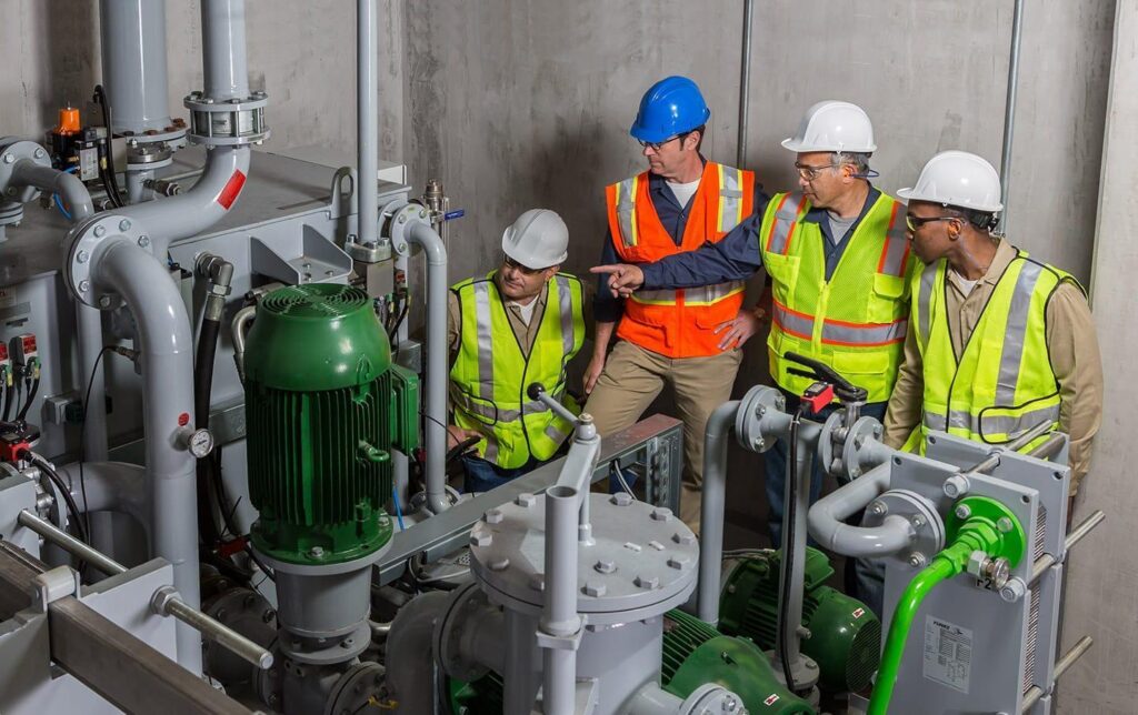 Four industrial workers monitoring air systems in a plant.